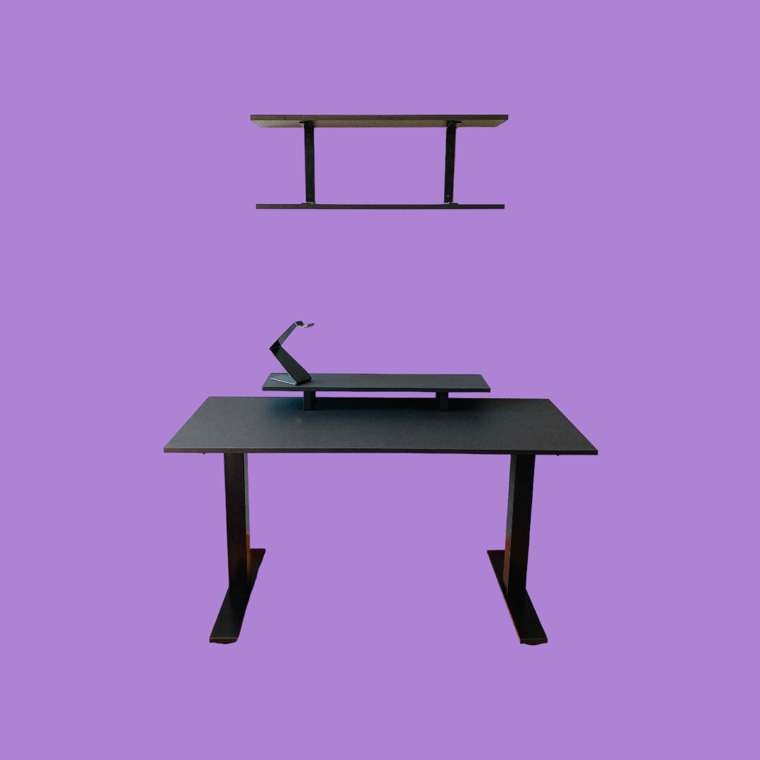 Matte black desk with a matte black desk frame, a matte black monitor riser with matte black feet and a matte black headphone stand, and a matte black wall shelf with matte black brackets.