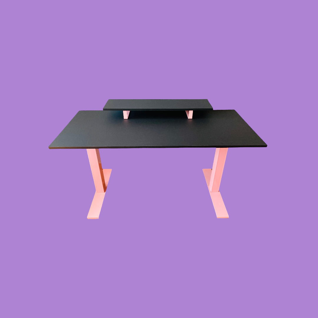 Matte black desk with a pink desk frame and a matte black monitor riser with pink feet.