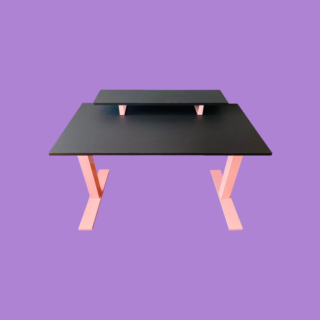 Matte black desk with a pink desk frame and a matte black monitor riser with pink feet.