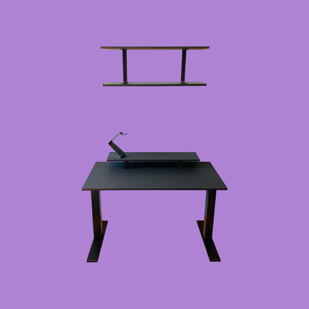Matte black desk with a matte black desk frame, a matte black monitor riser with matte black feet and a matte black headphone stand, and a matte black wall shelf with matte black brackets.